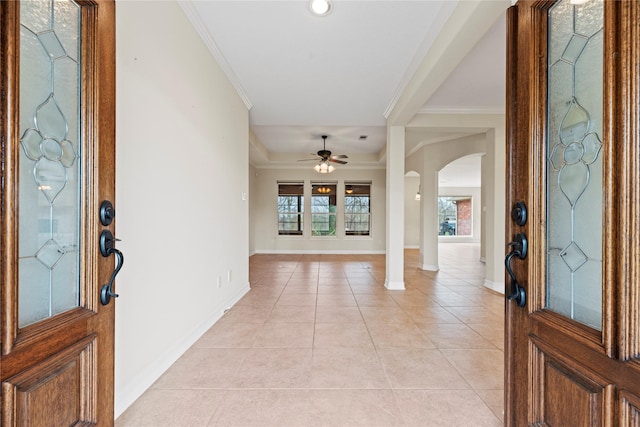 foyer with baseboards, arched walkways, crown molding, and light tile patterned flooring