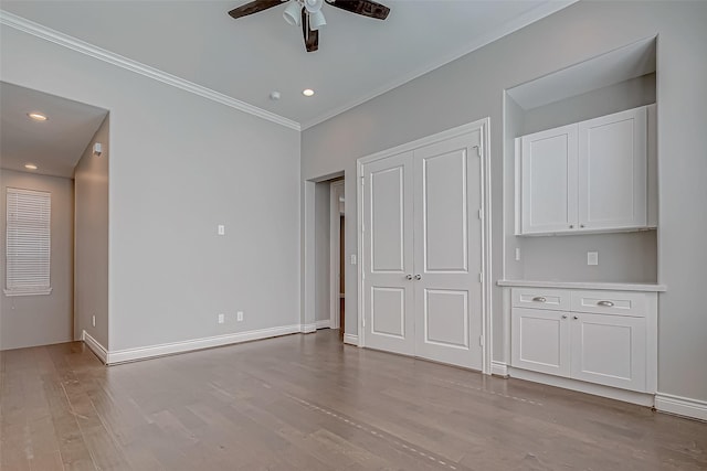 interior space with ceiling fan, ornamental molding, light wood-style flooring, and baseboards