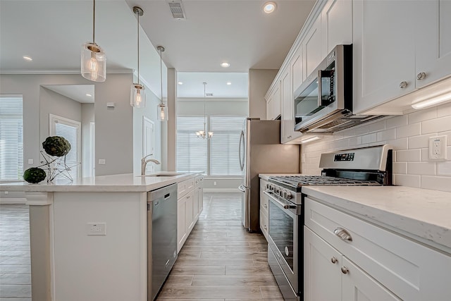 kitchen featuring visible vents, white cabinets, hanging light fixtures, stainless steel appliances, and a sink