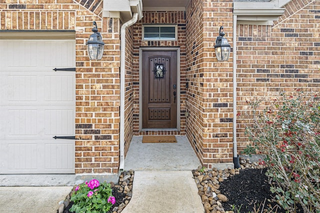 property entrance featuring a garage and brick siding