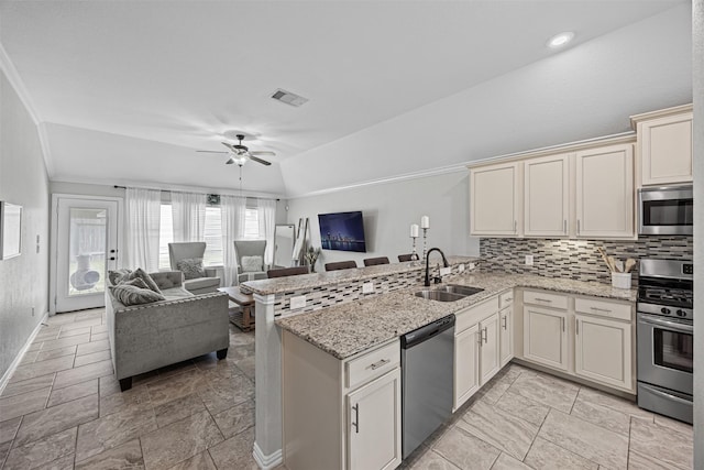 kitchen featuring open floor plan, a peninsula, appliances with stainless steel finishes, and a sink