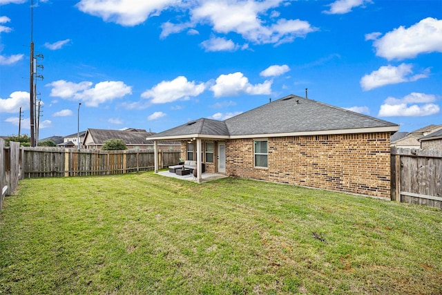 rear view of house featuring a yard, a patio, brick siding, and a fenced backyard