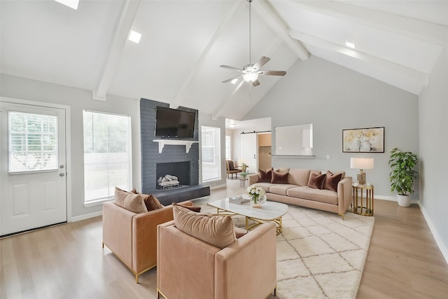 living room featuring a brick fireplace, ceiling fan, light wood-style flooring, and a barn door