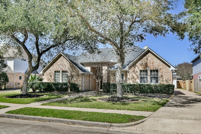 view of front of property featuring stone siding, a front lawn, a chimney, and fence