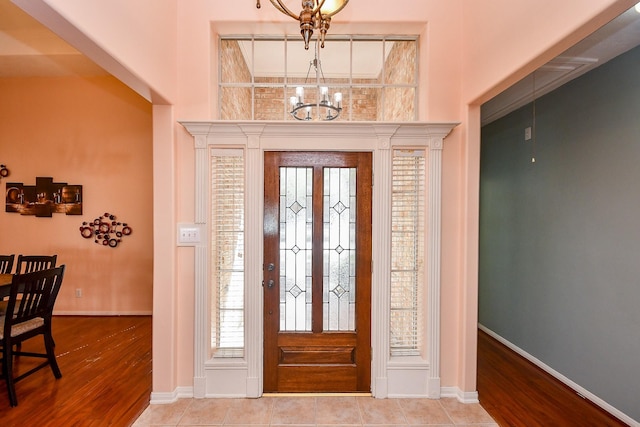 entrance foyer with a chandelier, wood finished floors, and baseboards