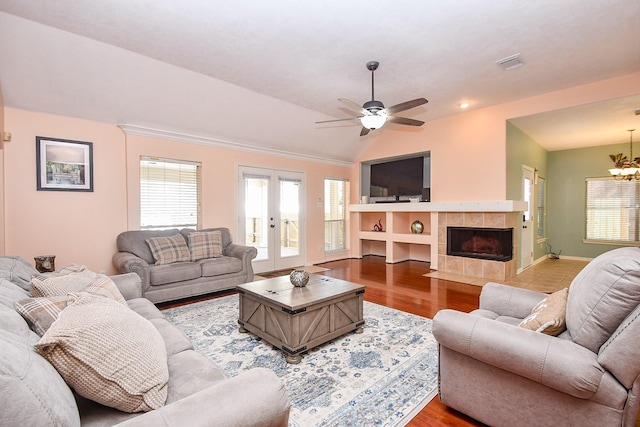 living room with wood finished floors, a wealth of natural light, a tile fireplace, and visible vents