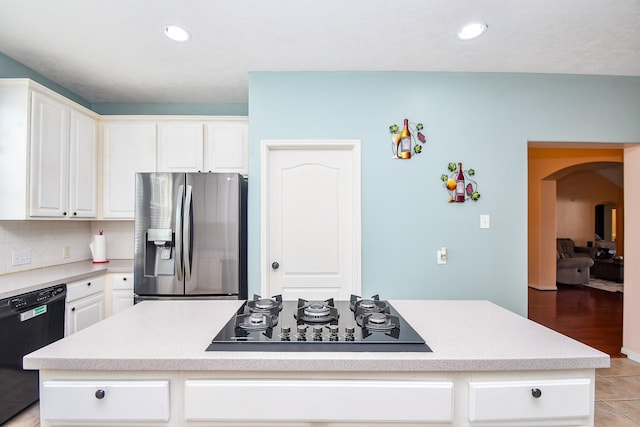 kitchen with arched walkways, white cabinets, a kitchen island, black appliances, and backsplash