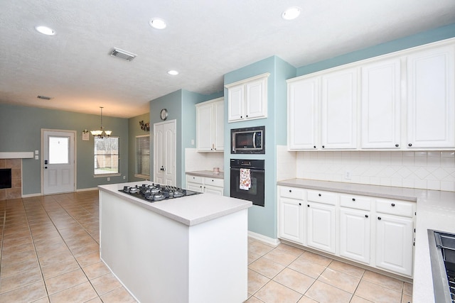 kitchen with black appliances, a kitchen island, visible vents, and light tile patterned flooring