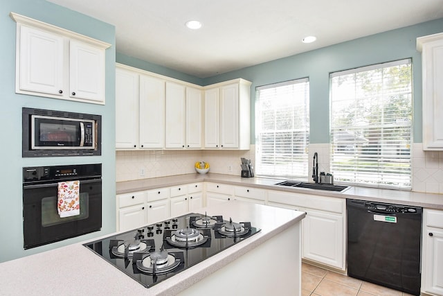 kitchen featuring black appliances, light tile patterned flooring, a sink, and a healthy amount of sunlight