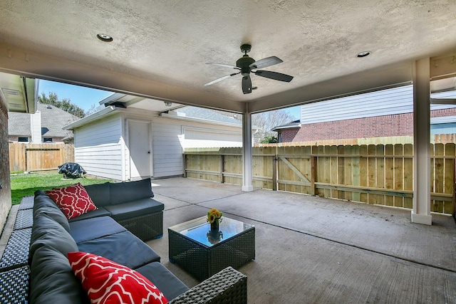 view of patio / terrace with ceiling fan, fence, outdoor lounge area, and an outbuilding