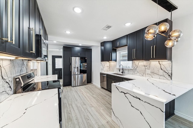 kitchen featuring light wood-style flooring, stainless steel appliances, a sink, visible vents, and light stone countertops