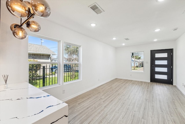 foyer featuring baseboards, a wealth of natural light, visible vents, and light wood-style floors