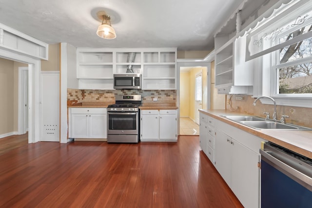 kitchen featuring white cabinetry, appliances with stainless steel finishes, open shelves, and a sink