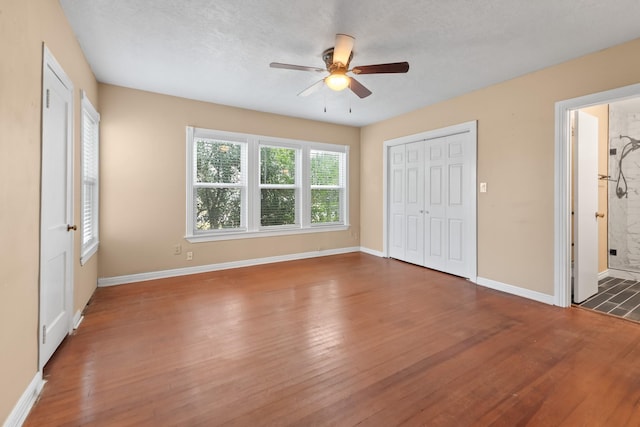 unfurnished bedroom with a ceiling fan, a closet, dark wood finished floors, and baseboards