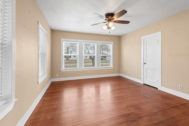 empty room featuring dark wood-style floors, baseboards, and a ceiling fan