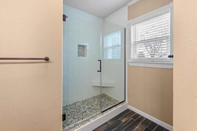 full bath with a stall shower, baseboards, and wood finish floors