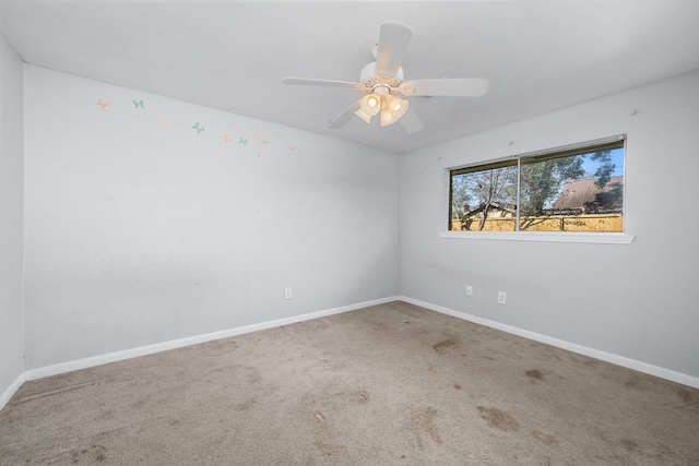 carpeted empty room with ceiling fan and baseboards