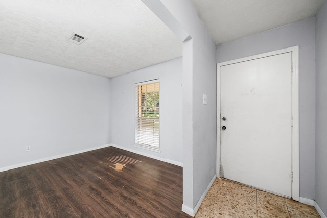 entrance foyer with visible vents, a textured ceiling, baseboards, and wood finished floors