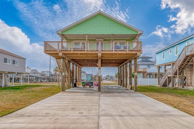 beach home with a carport, concrete driveway, a front lawn, and stairs