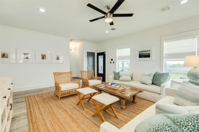 living area with recessed lighting, light wood-type flooring, visible vents, and crown molding