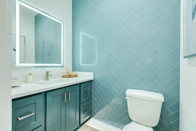 bathroom with toilet, tile walls, and vanity