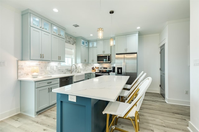 kitchen featuring stainless steel appliances, a kitchen island, visible vents, light stone countertops, and pendant lighting