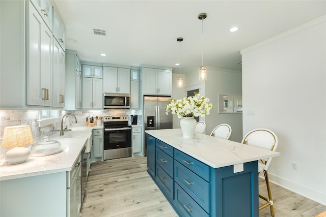 kitchen featuring a breakfast bar, pendant lighting, stainless steel appliances, visible vents, and a kitchen island