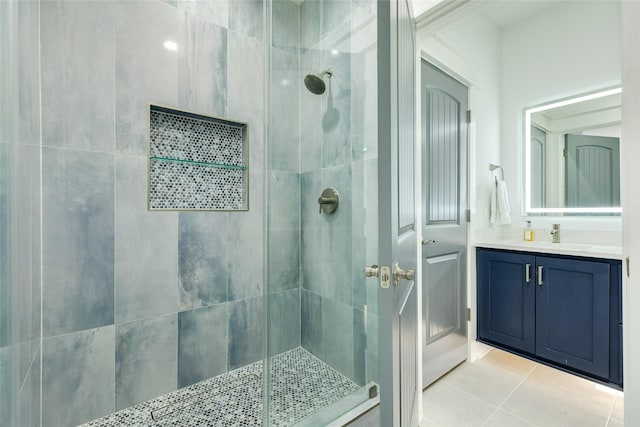 bathroom with tile patterned floors, a tile shower, and vanity