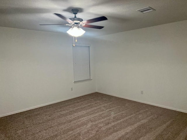 unfurnished room featuring visible vents, baseboards, ceiling fan, dark colored carpet, and a textured ceiling