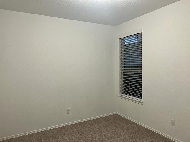 spare room featuring carpet flooring, a textured ceiling, and baseboards