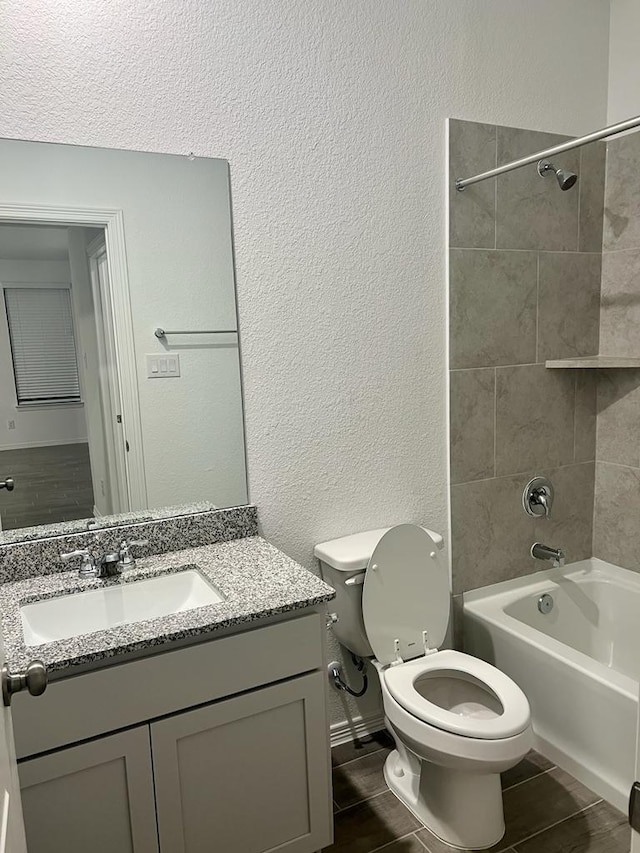 full bathroom with washtub / shower combination, a textured wall, toilet, and vanity