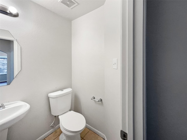 bathroom featuring tile patterned flooring, toilet, a sink, visible vents, and baseboards