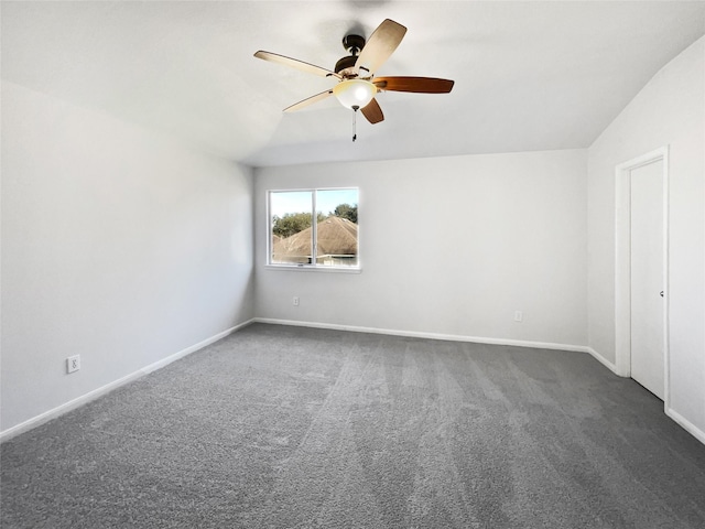 unfurnished room with vaulted ceiling, dark colored carpet, a ceiling fan, and baseboards