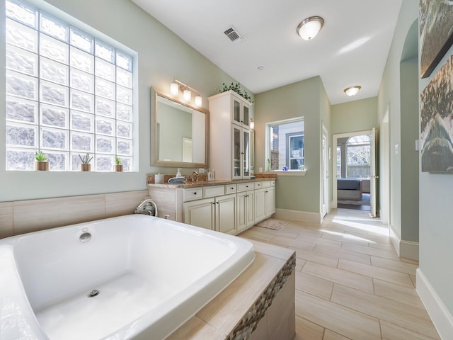 full bathroom with baseboards, visible vents, a bath, and vanity