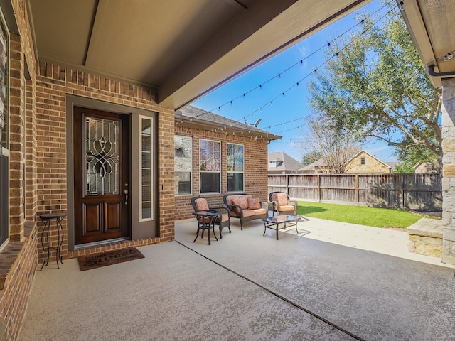 entrance to property with an outdoor hangout area, a patio, brick siding, and fence