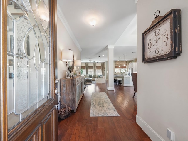 entrance foyer with dark wood-style floors, crown molding, baseboards, and decorative columns