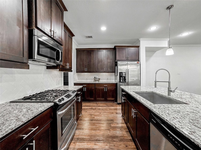 717 Via Lago, Webster, TX 77598 - kitchen with appliances with stainless steel finishes, a sink, crown molding, decorative light fixtures, and dark wood-style floors