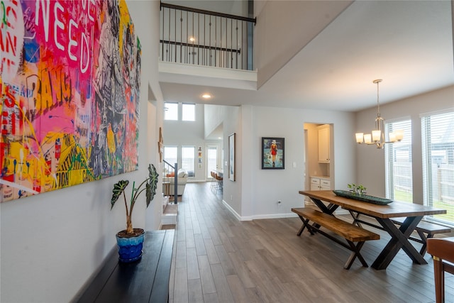 interior space featuring a high ceiling, a notable chandelier, baseboards, and wood finished floors