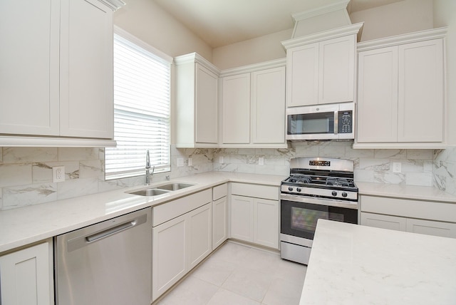 kitchen featuring tasteful backsplash, white cabinetry, stainless steel appliances, and a sink