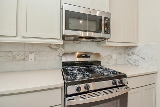 kitchen with stainless steel appliances, tasteful backsplash, light countertops, and white cabinets