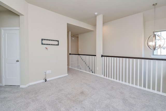 spare room featuring baseboards, a notable chandelier, and carpet flooring