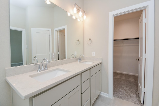 bathroom with double vanity, baseboards, a walk in closet, and a sink