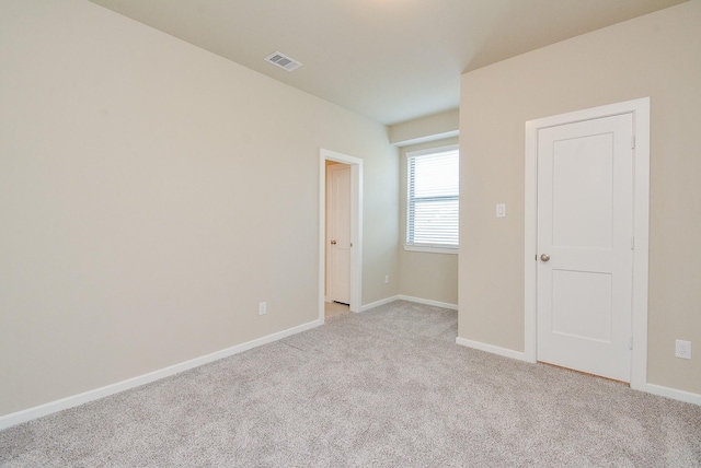 spare room featuring light carpet, visible vents, and baseboards