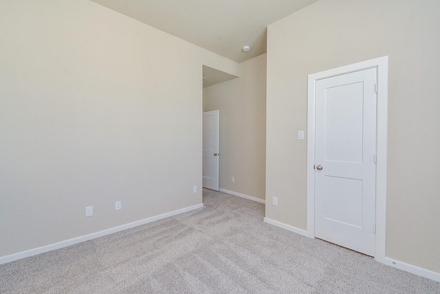 spare room with light colored carpet and baseboards