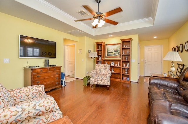 living area featuring ceiling fan, a tray ceiling, dark wood finished floors, and crown molding