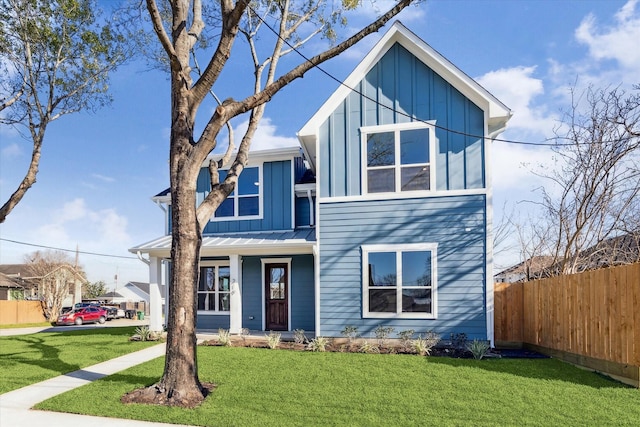 view of front of house with board and batten siding, a standing seam roof, fence, and a front lawn