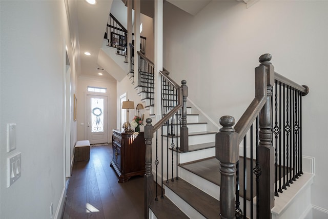 interior space featuring baseboards, hardwood / wood-style flooring, a high ceiling, crown molding, and recessed lighting