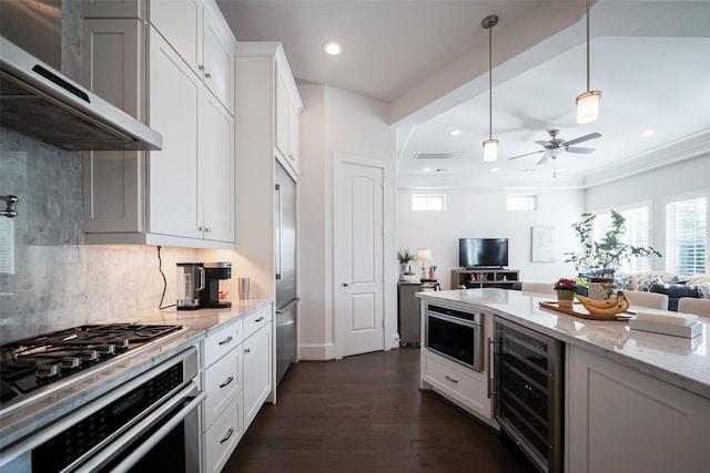 kitchen featuring wall chimney exhaust hood, wine cooler, appliances with stainless steel finishes, open floor plan, and white cabinetry