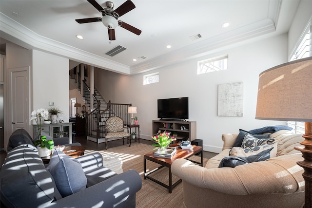 living room featuring visible vents, crown molding, and stairway