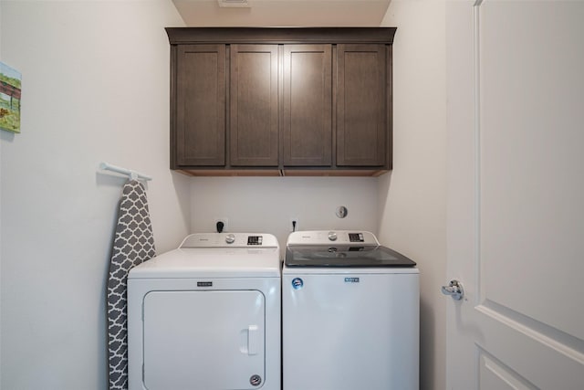 clothes washing area featuring cabinet space and independent washer and dryer